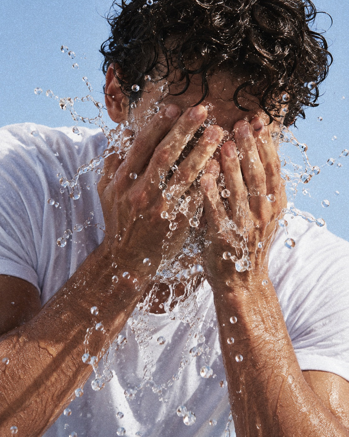 Man rinsing his face with water outdoors