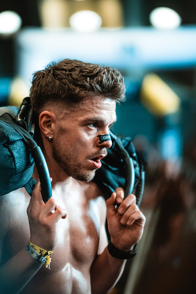 HYROX athlete mid-race breathing through nasal strip during station transition.